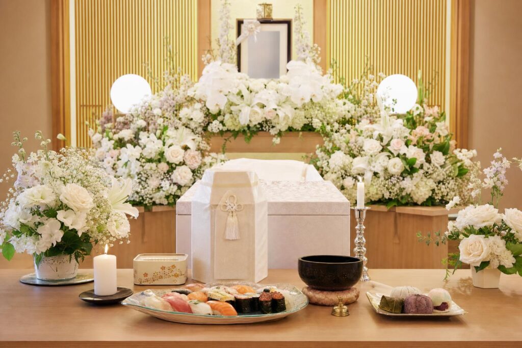 生花祭壇、お寿司やお菓子(和菓子)が供えられている